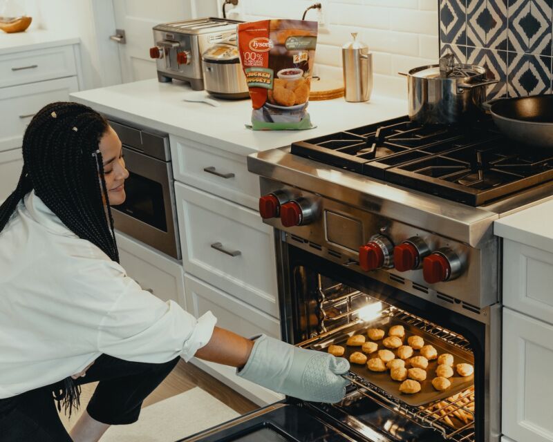woman in white long sleeve shirt standing in front of stainless steel dual fuel oven