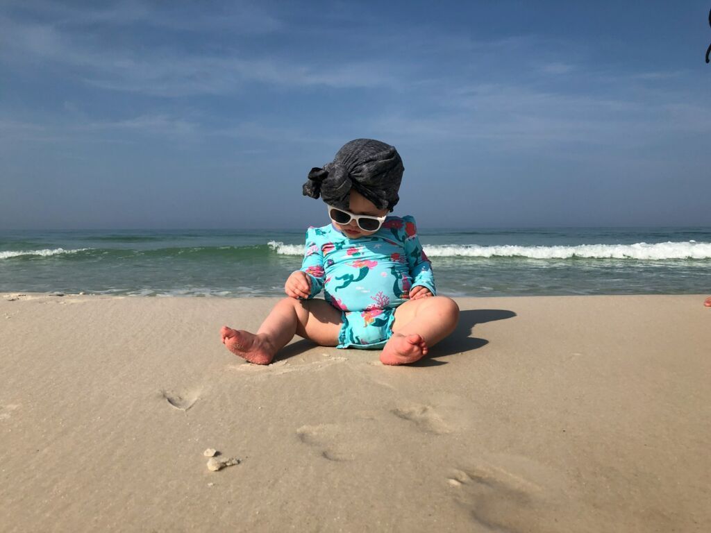 baby sitting near shore