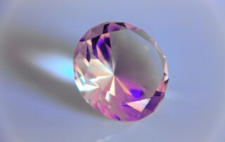 a close up of a lab grown pink diamond on a white background