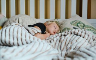 a little girl sleeping in a bed with a blanket - is it adhd or bad sleep