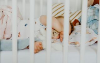 A baby peacefully sleeping with a pacifier in a cozy crib with plush blankets.