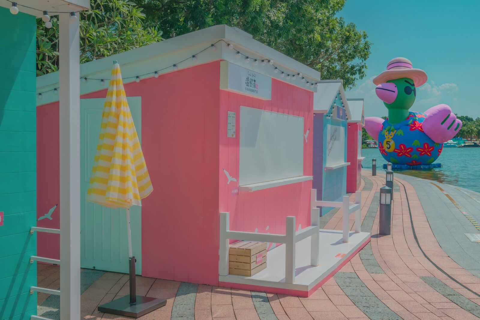 a pink and blue beach hut next to a body of water