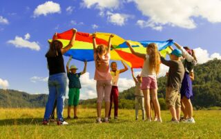children playing with colorful parachute on grass