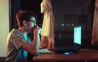 woman in brown shirt sitting in front of laptop computer