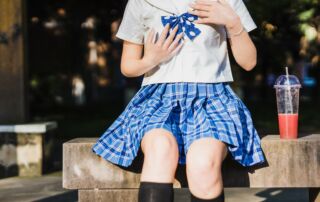 person in white and blue school uniform seating on beach with cup