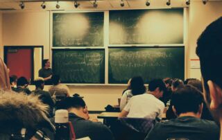 student sitting on chairs in front of chalkboard