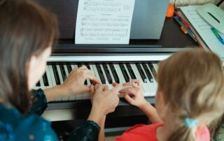 a woman and a little girl playing a piano
