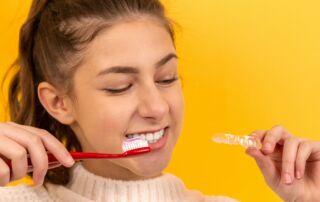 smiling girl in white sweater holding red and white toothbrush