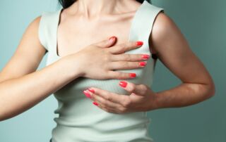Woman performing breast self-examination against a teal background