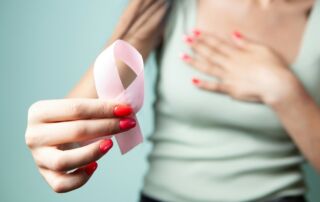 Woman holds pink ribbon for breast cancer awareness