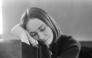 A young woman with eyes closed resting her head